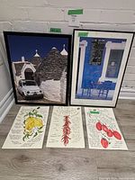Photo showing two framed photographic prints and three unframed illustrated recipe prints laid on floor