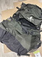 Overview of Dana Design Glacier internal frame camping pack in dark green and black with adjustable straps and padded hip belt, showing used condition and one broken buckle.