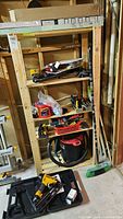 Overall view of shelving unit with various tools including a red Job Mate shop vacuum and a basket with hand tools
