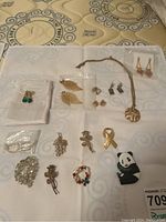 Overview of the collection showing multiple brooches and earrings arranged on a white cloth.