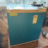 Photo of teal blue RCA mini fridge exterior with sticker indicating dimensions and model.