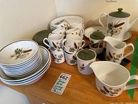 Full set of Johnson Brothers Brookside pattern ironstone china including stacked dinner plates, bowls, cups, saucers, serving pieces all decorated with botanical green and brown leaf and flower designs.
