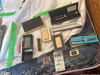 Overview of all items including lighters, pens in boxes, money clip, and lighter case.
