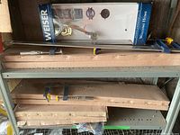 Full shelf view showing boxed Weiser lock set and eight F-clamps with metal bars and yellow handles