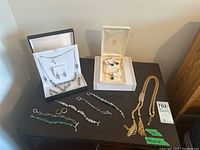 Full view of all jewellery pieces on display including boxed Nina Ricci set with ring and earrings, gold-tone tassel lariat necklace, several bracelets and a Fifth Avenue Collection multi-colored bracelet.