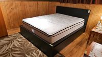 Angled view of assembled black platform bed with pillow top mattress