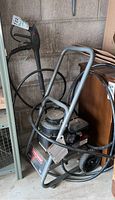 Full view of Craftsman pressure washer mounted on metal cart with hose and wand coiled around it, placed near wall in garage.