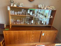 Front view of two-piece teak cabinet set with buffet below and hutch above showing glass and wood doors
