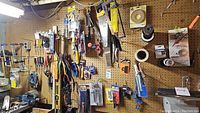 Wide view of pegboard loaded with hand tools including levels, clamps, screwdrivers and tape