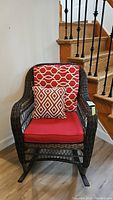 Front view of wicker rocking chair with reversible cushions, patterned side visible on the back cushion.
