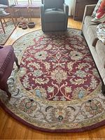 Oval rug in living room, showing full shape and placement among sofa, chair, and side tables
