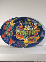 Frontal view of the oval plaque showing the full ocean scene with fish and boat