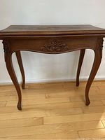 Full view of antique Dutch card table showing curved legs and floral carvings on apron and legs.