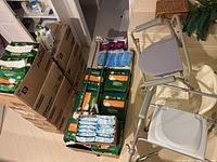 Overview of Depend packs, Poise pads, masks, Cetaphil bottles, commode and shower chairs