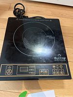 Top view of black Duxtop induction cooktop showing circular induction cooktop surface and control panel with buttons and digital display.