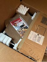 Photo showing the open box of the food dehydrator with the Dehydration Guide booklet on top and styrofoam inserts for protection.