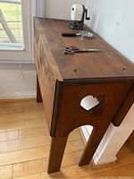 Side angled view of rectangular wooden hall table showing surface wear and heart cutout on one side panel.