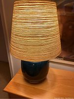 Lamp lit on top of mini dresser showing base, shade, and overall appearance