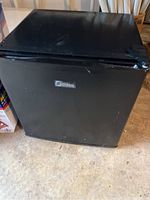 Black Midea mini fridge front, closed door with minor wear on surface.