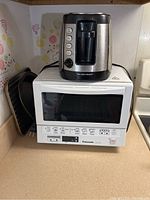 Panasonic toaster oven on counter with Hamilton Beach toaster on top, showing overall condition and design.