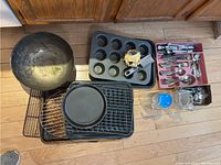 Overall view of baking pans, metal racks, cupcake tin, blue and glass cups, and cutlery in red tray