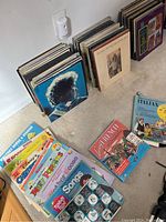 Photo showing multiple stacks of assorted vinyl records on the floor leaning against the wall and a box set Living French language course on the floor.