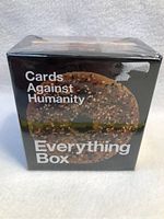 Front of Cards Against Humanity Everything Box sealed with shrink-wrap, featuring a multigrain bagel image.