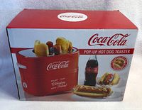 Box of Coca Cola Pop-Up Hot Dog Toaster showing product branding, images of hot dogs, and Coca Cola bottle.