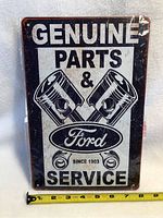 Front view of the rectangular Ford tin sign with piston graphics and text.