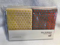 Tea towels set new in original packaging, two towels side by side with visible dot pattern in yellow and orange dots.