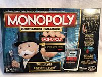 Front of Monopoly Ultimate Banking boxed game with mascot holding electronic bank card, showing logo and key features.