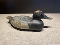 Side view of the duck decoy showing curved body, head, and worn painted surface
