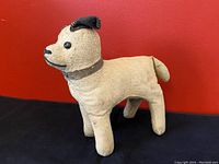 Front angle view of antique stuffed dog toy showing texture, color, and button eyes.