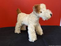 Front, side, and angled views of the antique Merrythought dog stuffed toy made of mohair with brown ears and tail, glass eyes, and black nose