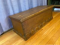 Angle view of the full antique pine sailors chest showing wave detail along bottom edge.