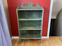 Front view of the entire shelf unit showing three shelves and decorative back pediment.