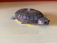 Side view of the carved wooden turtle decoy showing detailed shell and attached metal fins and hooks