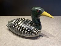 Front angle view of hand carved wooden loon decoy with detailed painted patterns showing a green head and yellow beak.