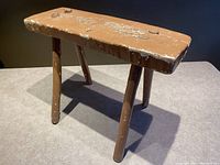 Front angle view of the wooden stool showing pegged construction and paint wear.