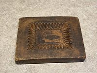 Top down angled view of the rectangular carved wood butter mold showing detailed maple leaf pattern.