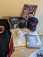 Baseball memorabilia with two baseball caps (Black Sox Baltimore, Negro Leagues Baseball Museum), a boxed 2017 Washington Nationals snow globe, Rawlings baseball in wrapper, vintage baseball cards 2019 calendar, MLB All Star Game 2018 postcard limited edition with stamp, book 'Fight to the Finish', and baseball bat pen on a cabinet.