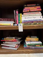 Books on a wooden shelf, mixture of paperbacks and hardcovers, including word search and reference titles.