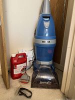 Full view of Kenmore PowerSpin carpet cleaner with carpet shampoo, vacuum filters, and brush attachment on carpet floor near corner of room.