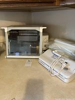 Photo showing Ronco Compact Showtime+ Rotisserie & BBQ Oven with FoodSaver Mini Plus vacuum sealer and bags on countertop.