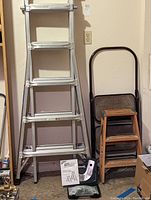 Werner telescoping multi-ladder standing fully extended against wall with hinge kit box and manual on floor