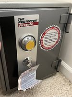 Closed fire safe showing combination dial lock with key lock below. Fire safe branding on front panel.