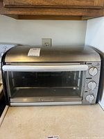 Frontal view of the Kenmore stainless steel toaster oven showing glass door and control knobs.