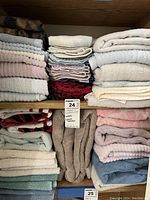 Stacks of various bath towels and washcloths in neutral and pastel colors, shown folded on shelf