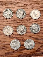 Eight U.S. nickels arranged on wooden surface showing fronts with varying wear and visible dates.