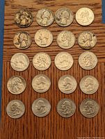 20 U.S. quarters arranged in 4 rows on a wooden surface showing varying levels of wear and patina.